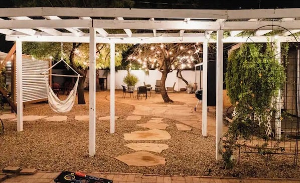 Ein überdachter Außenbereich mit Hängematte, Sitzgelegenheiten und einer Pergola.