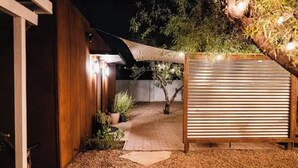 Un bâtiment en bois avec une clôture à lattes, un chemin pavé et un pot de fleurs.