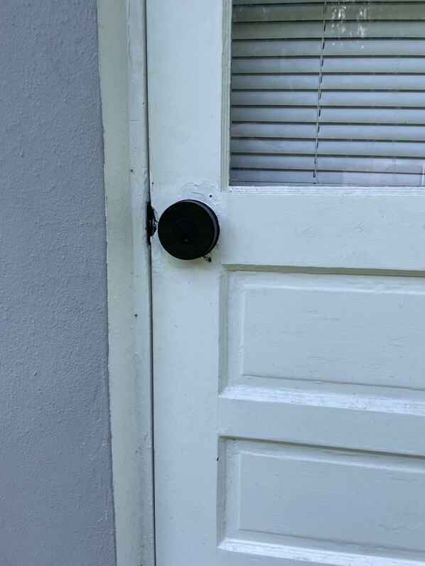 Une porte blanche avec une poignée noire et une fenêtre dotée de stores horizontaux.