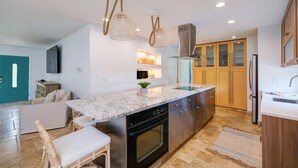 A modern kitchen with a central island, built-in oven, and wooden cabinets. - Casa Das Palmas | Beautiful 3 Bed/2 Bath Home with screened Heated Pool | Minutes to Anna Maria Island Beaches | Sleeps 8 (Bradenton)
