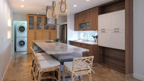 A modern kitchen with a central island, built-in appliances, and wicker chairs. - Casa Das Palmas | Beautiful 3 Bed/2 Bath Home with screened Heated Pool | Minutes to Anna Maria Island Beaches | Sleeps 8 (Bradenton)