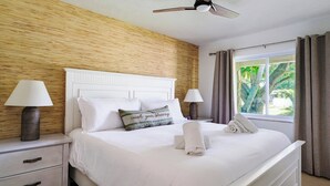 A hotel room with a bed, two bedside lamps, a nightstand, a window with curtains, and a ceiling fan. - Casa Das Palmas | Beautiful 3 Bed/2 Bath Home with screened Heated Pool | Minutes to Anna Maria Island Beaches | Sleeps 8 (Bradenton)