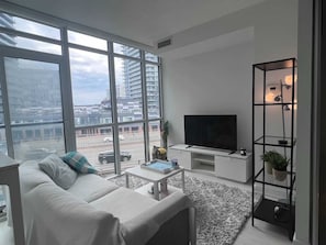 Relax in this stylish living room with a city view, featuring a sofa, coffee table, flat-screen TV, and a potted plant.