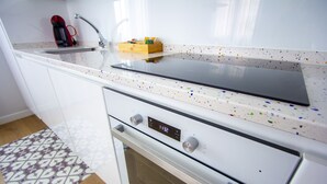 Una cocina moderna con horno de acero inoxidable, un reloj digital y una cafetera sobre la encimera.