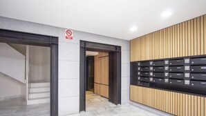Un vestíbulo moderno con una escalera, un cartel de no fumar y una fila de buzones.