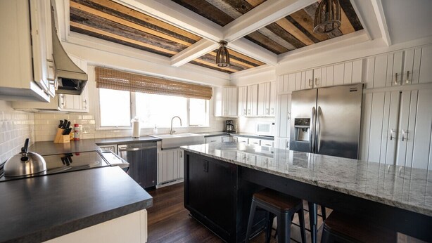 A modern kitchen with a large island, white cabinetry, and a wooden ceiling. - The Lodge|Hot Tub|Horses|Hiking|Wood Stove (Groveland Township)
