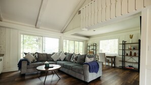 A spacious living room with a large sectional sofa, a round coffee table, and a bookshelf. - The Lodge|Hot Tub|Horses|Hiking|Wood Stove (Groveland Township)