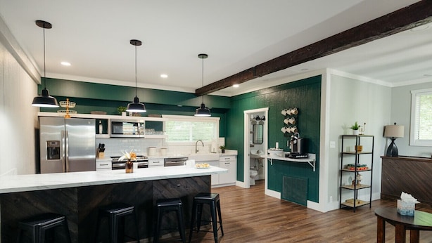 Una cocina moderna con una isla grande, taburetes de bar e iluminación colgante.
