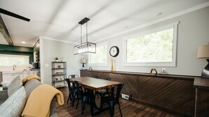 Una cocina moderna con comedor, suelo de madera y ventanas grandes.
