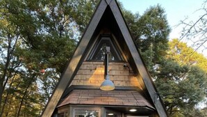 Una piccola casetta di legno con una porta scura e una finestra con tenda.