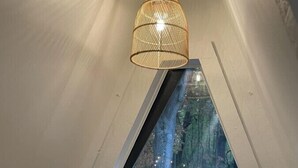 Una camera da letto con soffitto spiovente, un'ampia finestra e un lampadario.