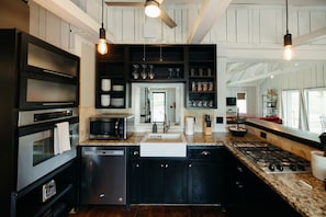 A modern kitchen with dark cabinetry, stainless steel appliances, and a central island.