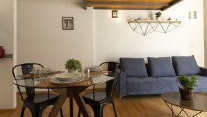 A modern living room with a glass dining table, black chairs, a blue sofa, and a wooden ceiling. - Prosperidad By HomiRent (Mexico City)