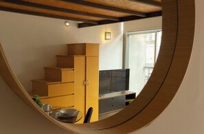 Een knus woongedeelte met een televisie, houten meubels en een raam.