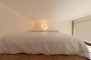 Een eenpersoonsbed in een kamer met een lichtgekleurde muur en een raam aan de rechterkant.