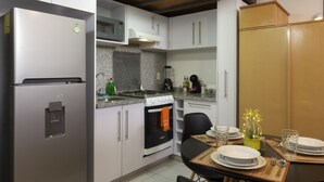 A modern kitchen with stainless steel appliances, white cabinetry, and a dining area set for four. - Prosperidad By HomiRent (Mexico City)