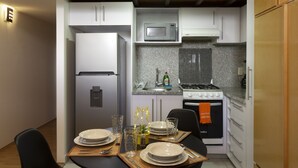 A compact kitchen with a refrigerator, microwave, stove, and sink. - Prosperidad By HomiRent (Mexico City)