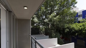 A balcony with a metal railing, a white wall, and a tree in the background. - Prosperidad By HomiRent (Mexico City)