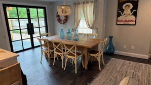 Een eetgedeelte met een houten tafel en stoelen, een kroonluchter en een poster aan de muur.