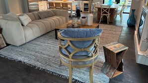 Een moderne keuken met roestvrijstalen apparatuur, een eetgedeelte met een houten tafel en stoelen, en een gezellige woonkamer met een bank en een vloerkleed met dessin.