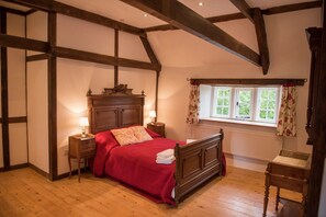Cozy bedroom with a four-poster bed, nightstands, and a comfortable chair.