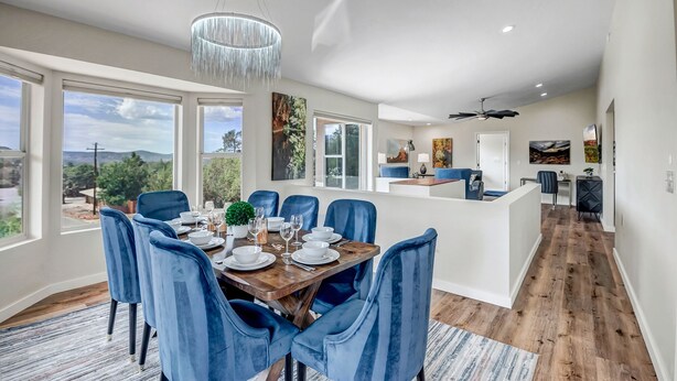 A modern dining area with a wooden table set for six, surrounded by blue upholstered chairs. - Experience luxury in this spacious 4-bedroom Sedona Maxwell Ridge with stunning red rock views. (Sedona)