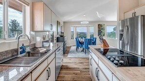 A modern kitchen with a central island, stainless steel appliances, and a view of the outdoors. - Experience luxury in this spacious 4-bedroom Sedona Maxwell Ridge with stunning red rock views. (Sedona)