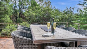An outdoor dining area with wicker furniture and a wooden table, surrounded by trees. - Experience luxury in this spacious 4-bedroom Sedona Maxwell Ridge with stunning red rock views. (Sedona)