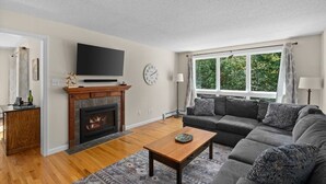 A living room with a fireplace, a sofa, a coffee table, and a TV mounted on the wall. - Timber Creek Retreat w/ Free Shuttle & Fireplace! (Dover)