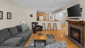 A living room with a sofa, coffee table, fireplace, and a TV mounted on the wall. - Timber Creek Retreat w/ Free Shuttle & Fireplace! (Dover)