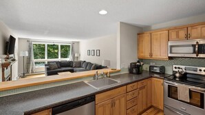 A modern kitchen with wooden cabinets, a stainless steel dishwasher, a microwave, and an oven. - Timber Creek Retreat w/ Free Shuttle & Fireplace! (Dover)