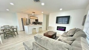 A modern living room with a sofa, a coffee table, and a TV mounted on the wall. - 4BR/3BA Mini-Resort Near Beach heated Pool & Spa (Pompano Beach)