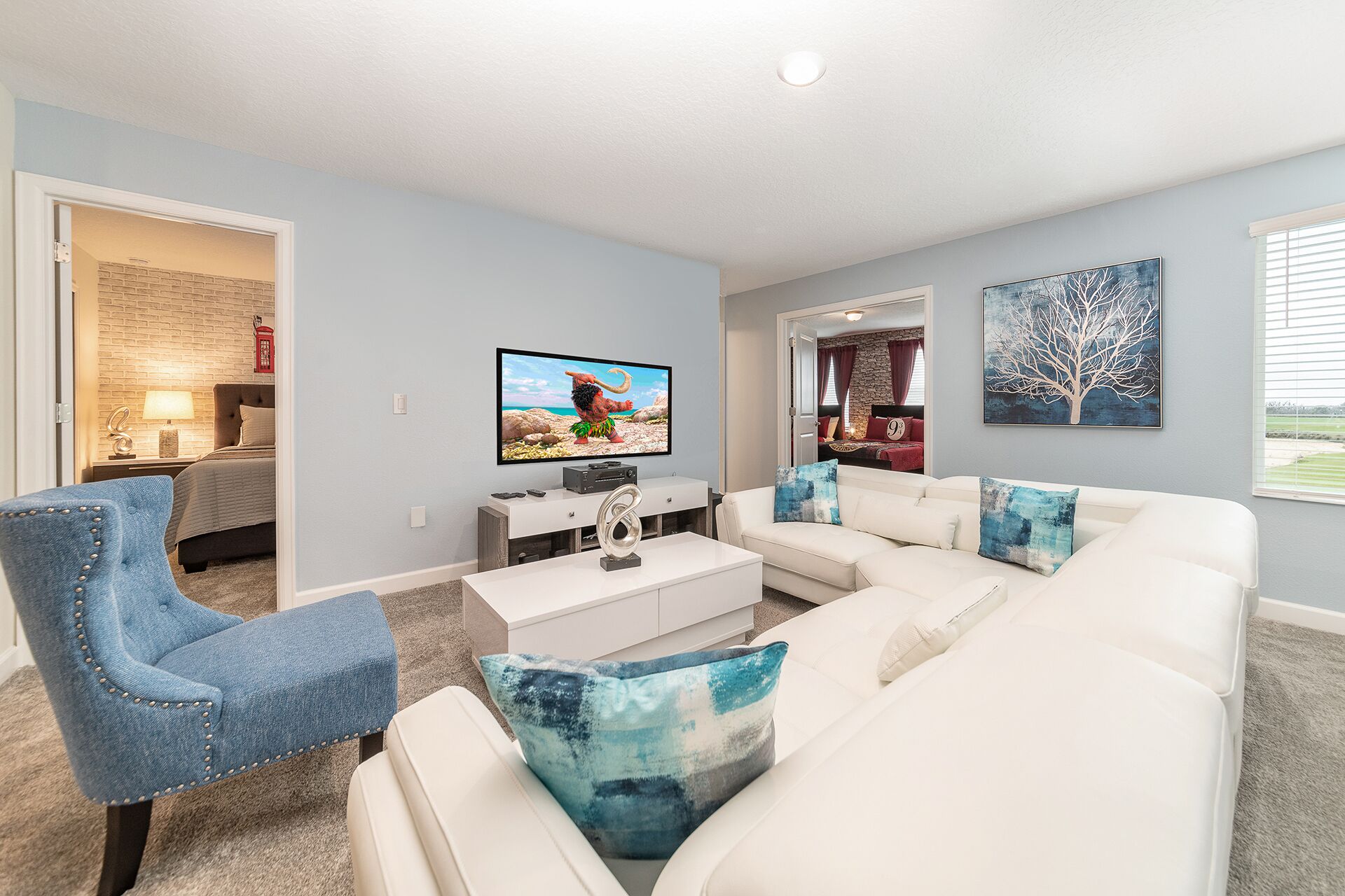 A modern living room with a white sofa, a blue armchair, and a flat-screen TV on a white stand.