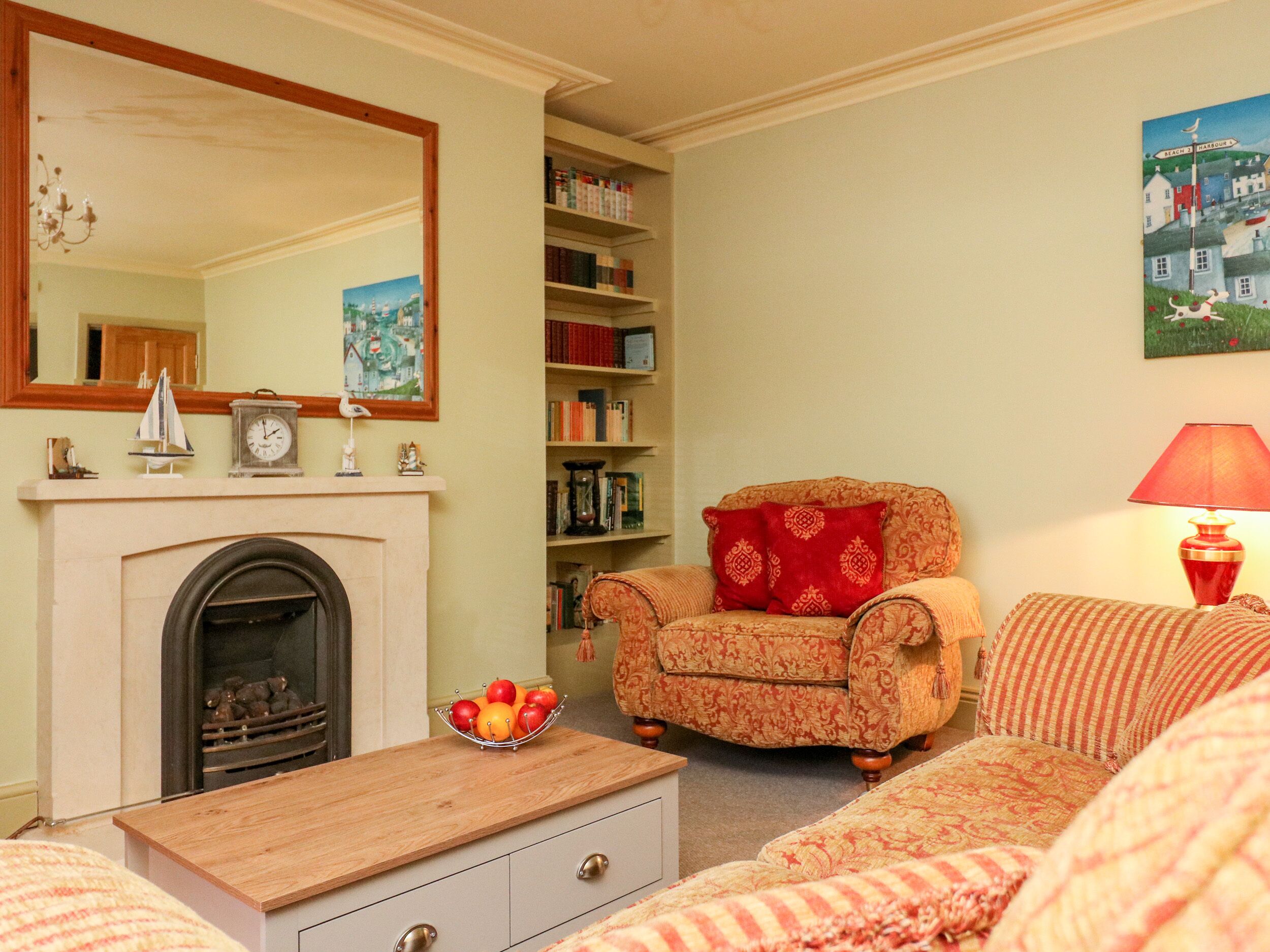 A cozy living room with a fireplace, a bookshelf, a comfortable armchair, and a dining table.