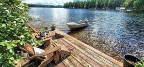 A wooden dock with a boat, potted plants, and a table.