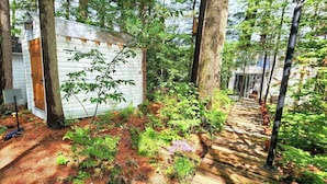 A wooden cabin surrounded by trees, with a dirt path leading to it. - Stabbin Cabin #2 on Grant Island-HotTub,Boat,Pets (BRANTINGHAM)