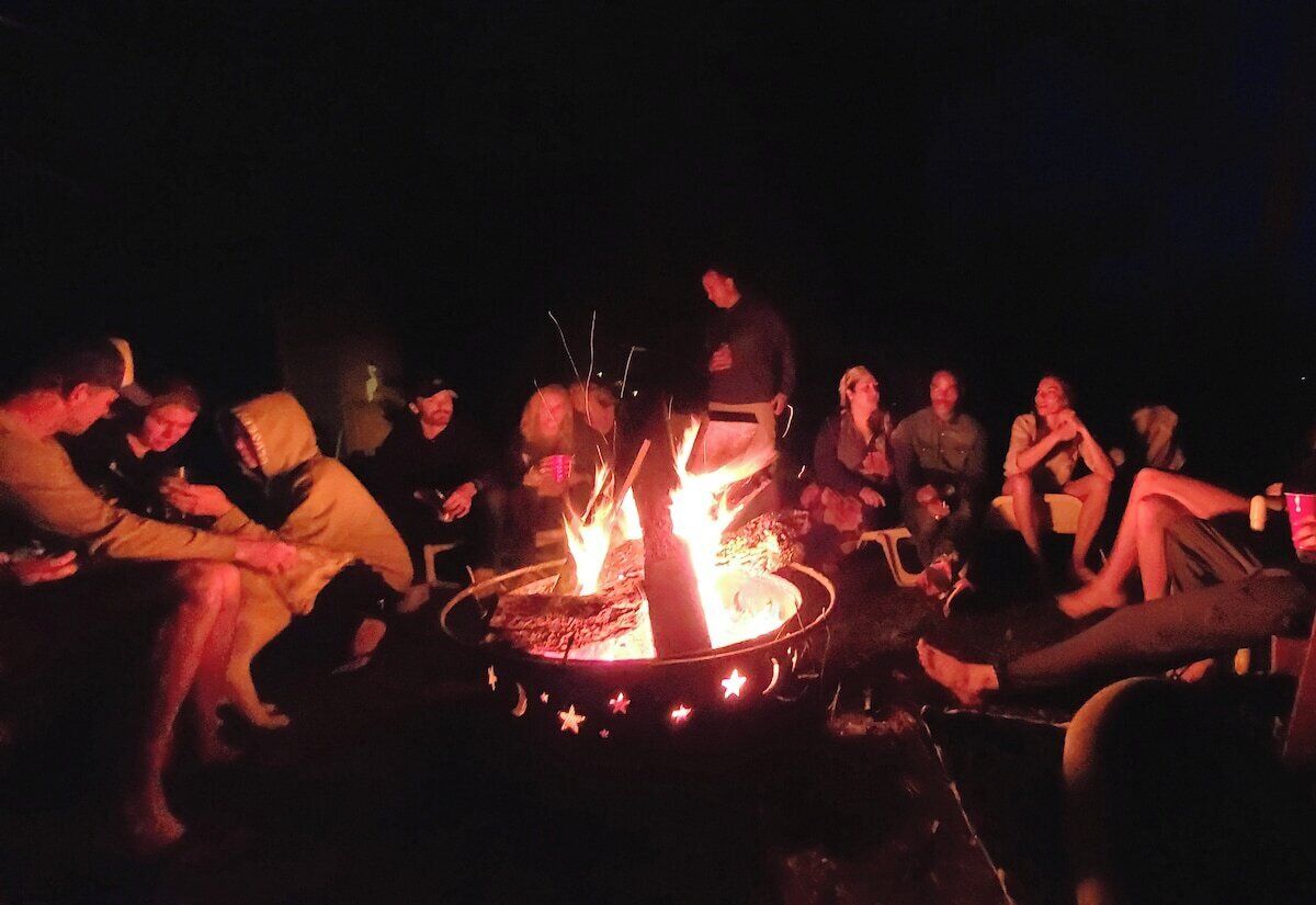 A group of people gathered around a campfire at night.