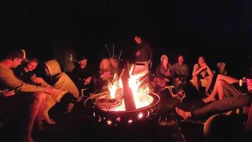 A group of people gathered around a campfire at night.