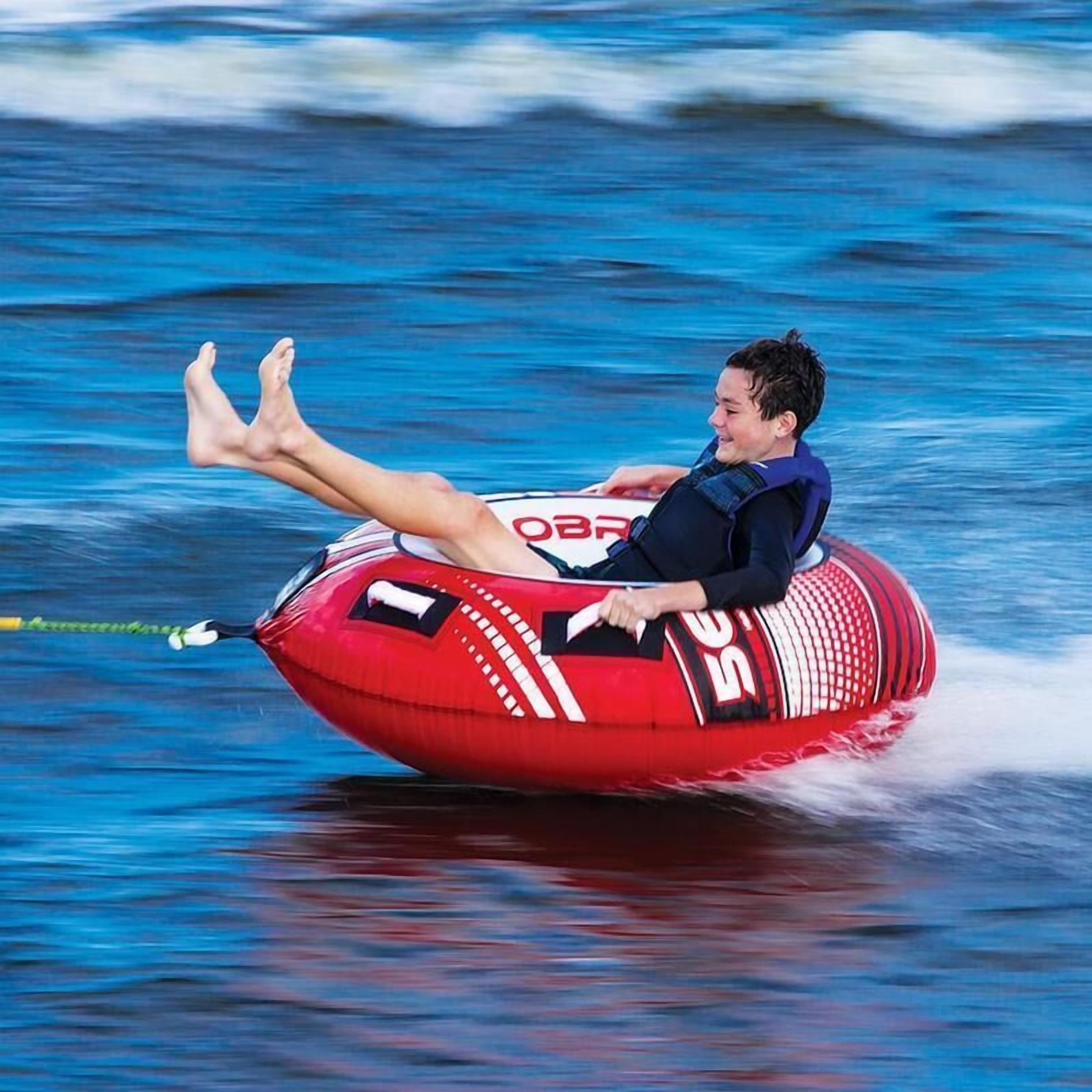 Una persona asseguda en un tub vermell inflable amb el número 50, flotant sobre l'aigua.