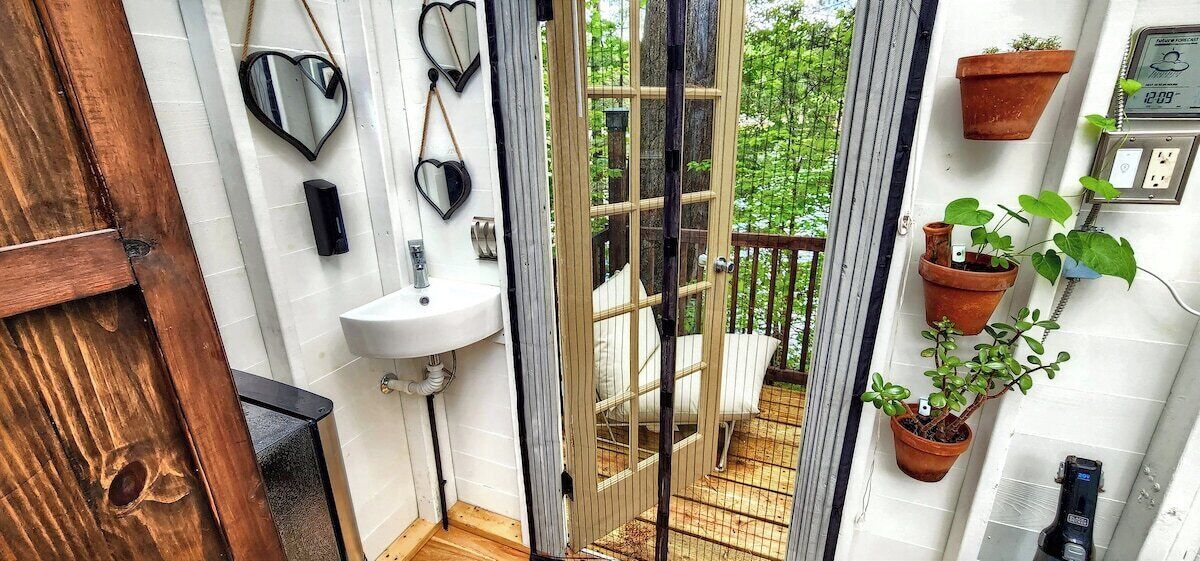 A bathroom with a sink, heart-shaped mirrors, and a view of a balcony with plants.