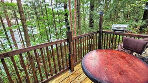 A wooden deck with a metal grill and a bench. - Stabbin Cabin #2 on Grant Island-HotTub,Boat,Pets (BRANTINGHAM)
