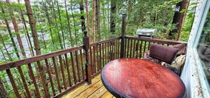 A wooden deck with a metal grill and a bench. - Stabbin Cabin #2 on Grant Island-HotTub,Boat,Pets (BRANTINGHAM)