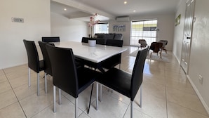 A modern dining area with a white table and black chairs, a potted orchid, and a view of the outdoors through large windows. - Comfort, Convenience, and Space – Modern Family Living in Annandale - Comfort, Convenience, and Space – Family Living in Annandale (Annandale)