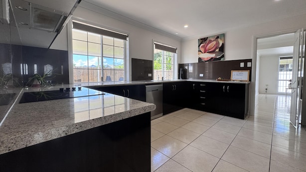 A modern kitchen with a granite countertop, black cabinets, and a large window providing natural light. - Comfort, Convenience, and Space – Modern Family Living in Annandale - Comfort, Convenience, and Space – Family Living in Annandale (Annandale)