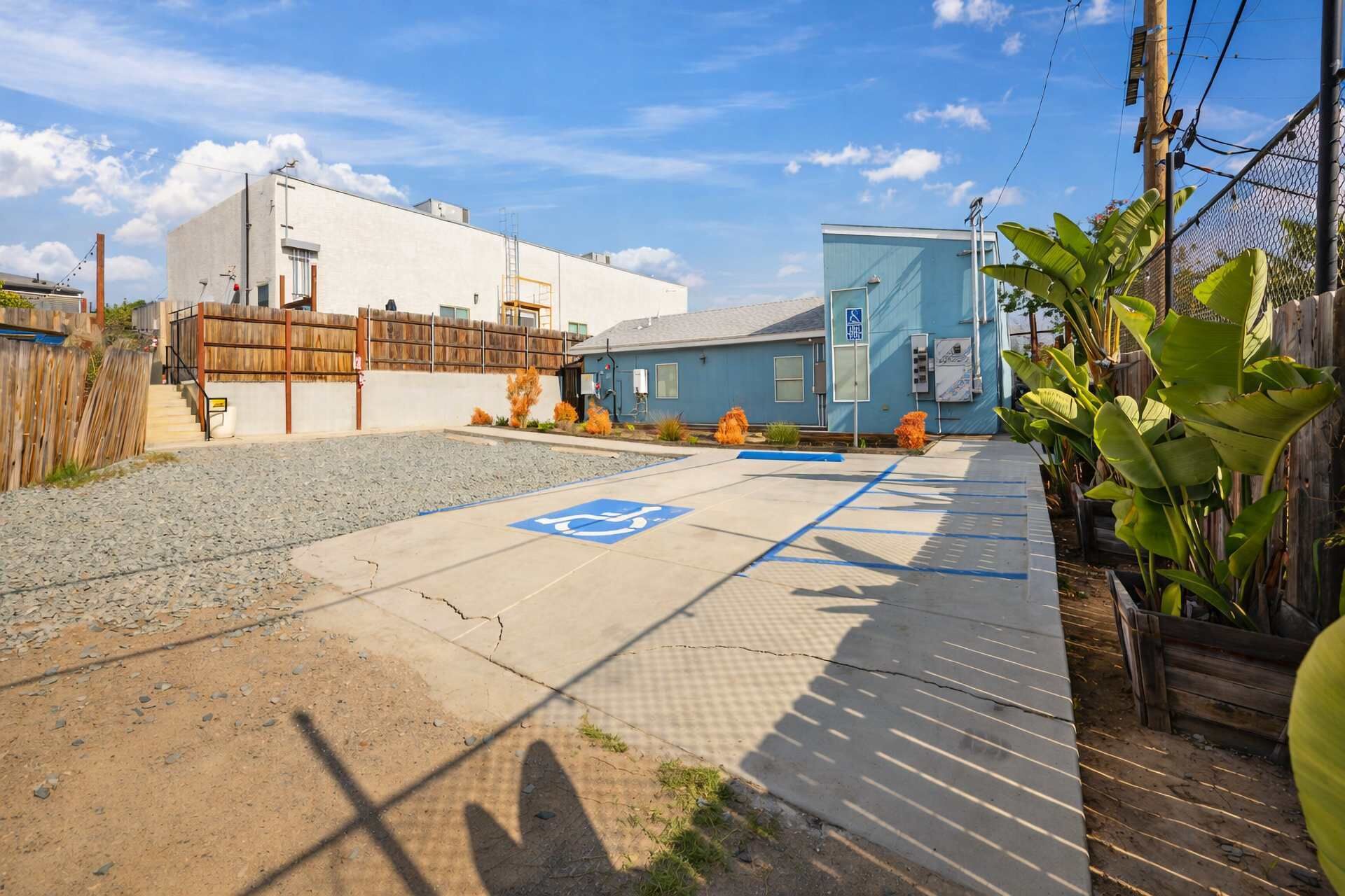 Un espace de stationnement comprenant une place réservée aux personnes handicapées, un bâtiment à l’extérieur bleu et une clôture en bois.