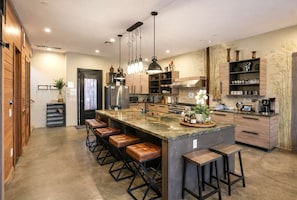 A modern kitchen with a large island, bar stools, pendant lighting, and built-in shelves. - 9BR Bamboo Loft * Near Downtown 21 bed 26 capacity (San Diego)