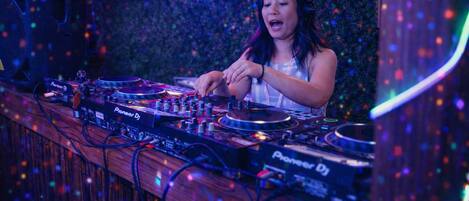 A DJ booth with Pioneer DJ equipment, surrounded by a wooden bar counter.