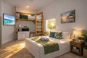 A bedroom with a bunk bed, a desk, a bed with pillows, a nightstand, a lamp, and a painting.