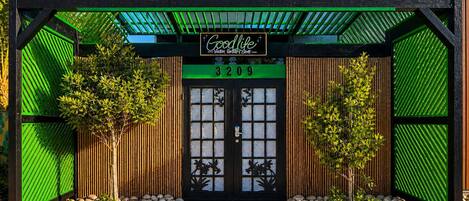 A building with a green and black facade, a sign reading 'Goodlife,' and a number '3209' above the entrance.