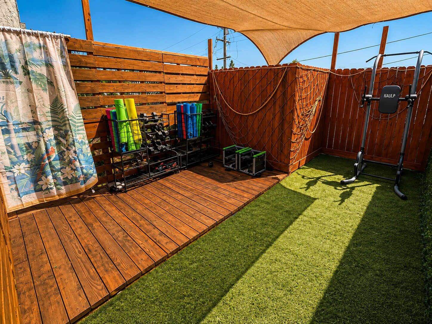 Een houten terras met kunstgras, een rek met fitnessapparatuur en een houten omheining.